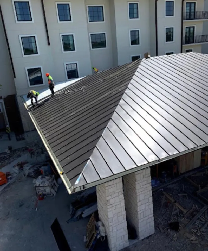 Crew installing standing seam metal roof panels on a commercial project in Dacula